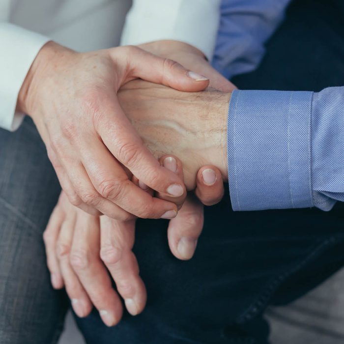 close up older elderly people hands. Old man holds a woman hand sitting together at home indoor. Senior couple mature family husband and wife grandparents together support trust in marriage. Closeup