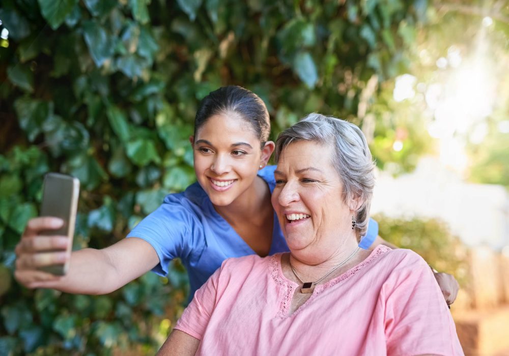 Cropped shot of a caregiver taking a selfie with a senior patient outside.